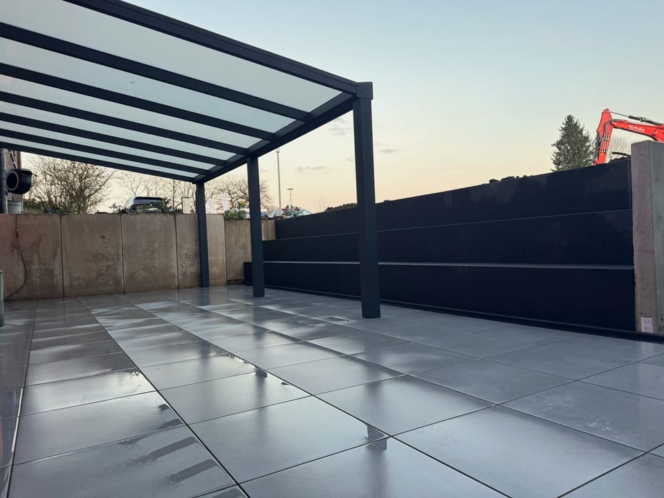 Terrasse mit Sitzstufen und L-Stein-Wand in der Abenddämmerung in Bielefeld
