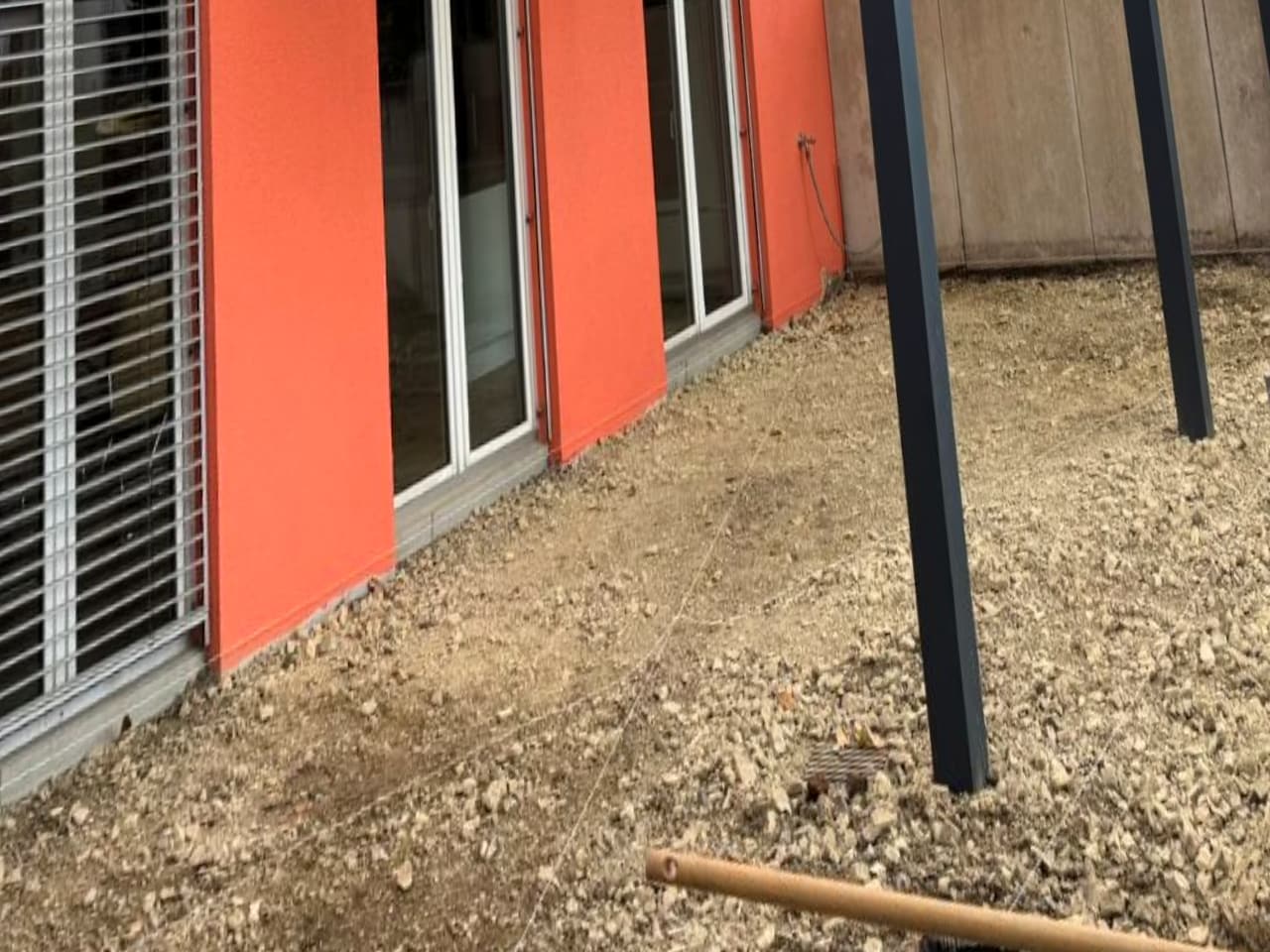 Vorher: verdichteter Schotterunterbau vor dem Haus in Bielefeld, das Terrassendach-Gestell steht bereits